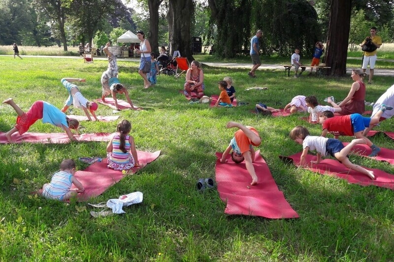 Kinder machen Yoga auf einer Wiese...alles ist bunt und sieht sehr fröhlich aus.